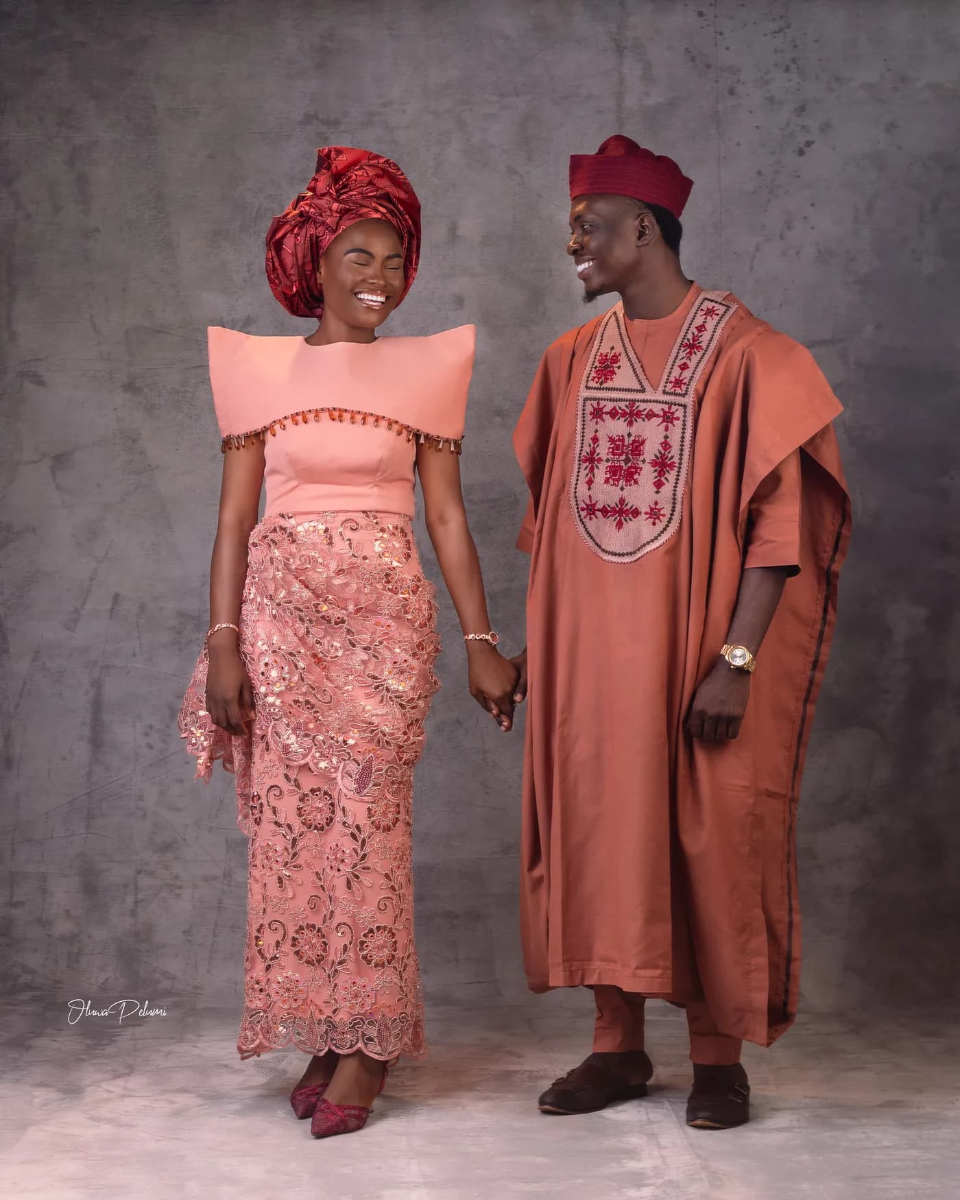Asepe and Ajibola in traditional Yoruba attire, holding hands and laughing