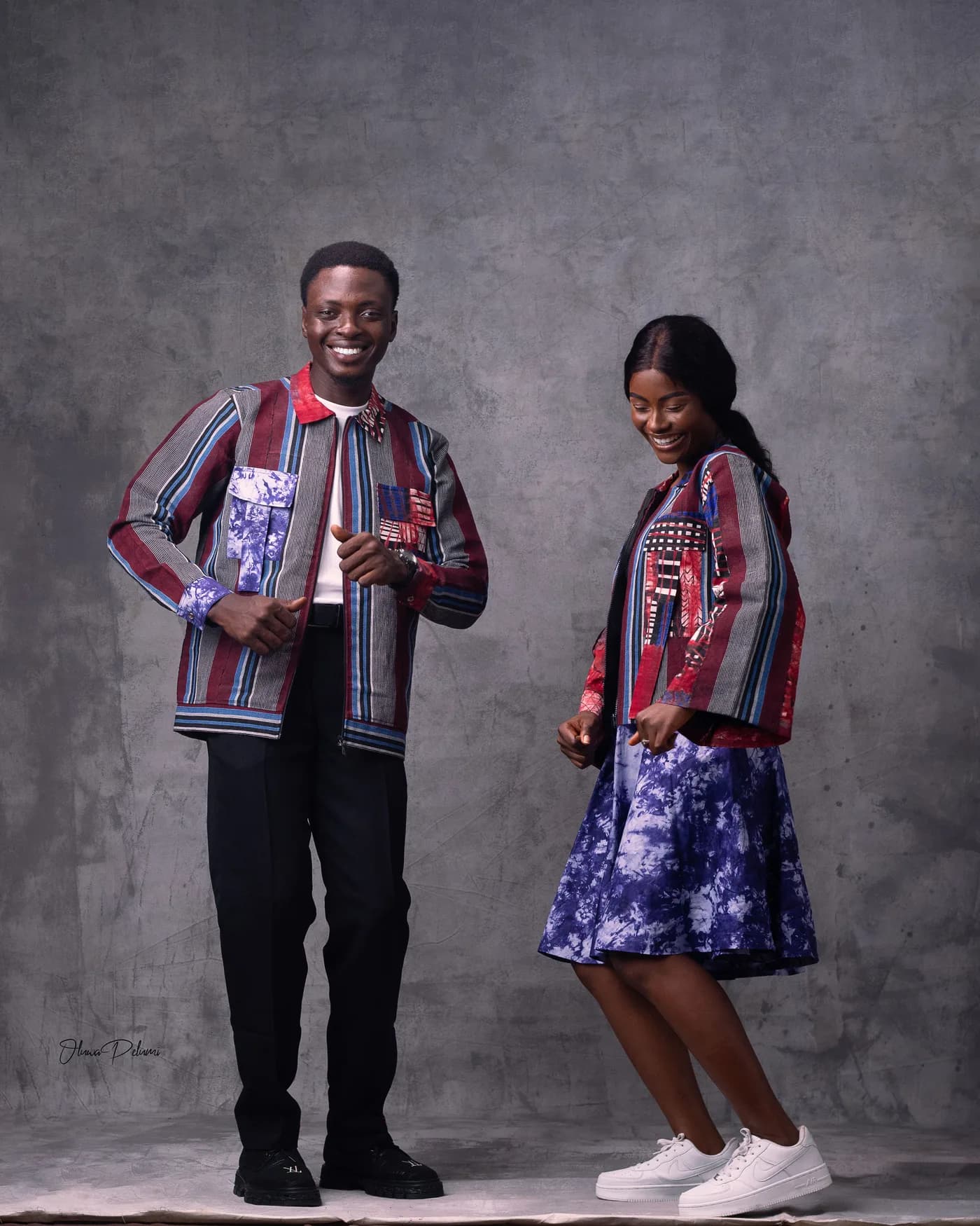 The couple dancing playfully in matching striped aso-oke jackets